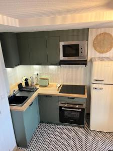 a small kitchen with a sink and a microwave at Tropical Duplex : Bord de mer + Piscine in Frontignan