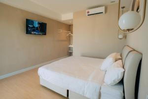 a bedroom with a bed with a tv on the wall at White Roses Cottage in Keningau