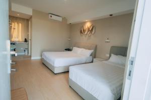 two beds in a hotel room with white sheets at White Roses Cottage in Keningau
