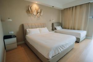 a bedroom with two beds with white sheets at White Roses Cottage in Keningau