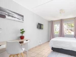 Leas Furnished Apartments - Capital Hill في بريتوريا: غرفة نوم بسرير ومكتب ونافذة