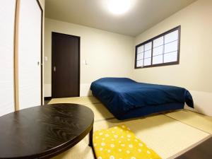 Un dormitorio con una cama azul y una mesa. en KAMON INN AIHUKA, en Kioto