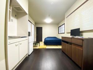 cocina con armarios blancos y cama azul en KAMON INN AIHUKA, en Kioto