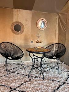 dos sillas y una mesa y una mesa y sillas en Aladdin Merzouga Camp en Merzouga