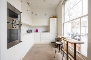 een keuken met witte kasten en een houten tafel bij Luxury and Cool 2 bedroom in Notting Hill in Londen