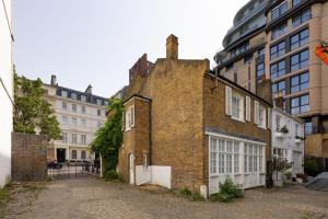 um antigo edifício de tijolos em frente a alguns edifícios em Traditional Treasure – 3 Bedroom Home by Hyde Park em Londres