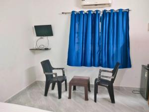 a room with two chairs and a blue curtain at Hotel Downtown Calangute in Calangute