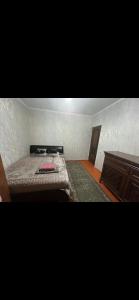 a room with a bed and a wooden table at Квартира in Shymkent