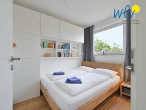 a bedroom with a bed with white walls and a window at Haus am alten Leuchtturm Ferienwohnung 16 in Wangerooge