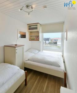 deux lits dans une petite pièce avec une fenêtre dans l'établissement Haus am alten Leuchtturm Ferienwohnung 8, à Wangerooge