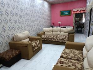 a waiting room with couches and chairs and pink walls at Homestay Bemban Batu Gajah in Batu Gajah
