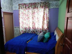 a bedroom with a blue bed with two pillows at Homestay Bemban Batu Gajah in Batu Gajah