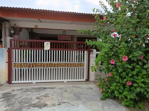 a house with a white gate and a bush with pink roses at Homestay Bemban Batu Gajah in Batu Gajah