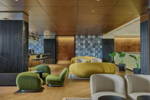 a lobby with yellow and green chairs and tables at Le Meridien Batumi in Batumi