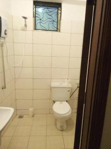 een badkamer met een toilet, een wastafel en een raam bij Suzie hotel Kampala Uganda old twon in Kampala