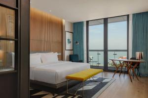 バトゥミにあるLe Meridien Batumiのベッド、デスク、テーブルが備わる客室です。