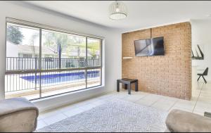 a living room with a brick wall and a flat screen tv at Mildura Holiday Villas in Mildura