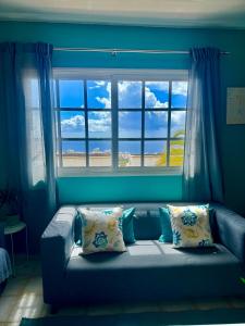 Sofá azul con almohadas frente a una ventana en Sunset View Balcon del Atlantico fase IV in Torviscas, en Adeje