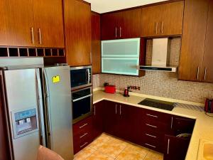 a kitchen with wooden cabinets and a white refrigerator at Athena Two-bedroom Townhouse in Paphos City