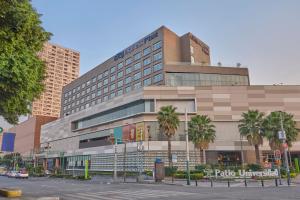 a large building with palm trees in front of a street at City Express Plus by Marriott Patio Universidad in Mexico City