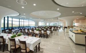 jadalnia ze stołami, krzesłami i oknami w obiekcie Grand Hotel Neum Wellness & Spa w Neum