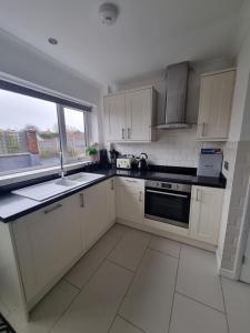 a kitchen with white cabinets and a sink and a window at The Retreat, Cromer in Cromer