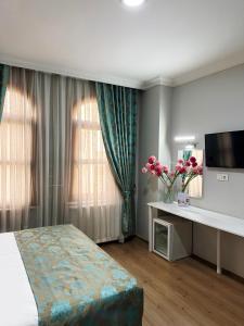 a hotel room with a bed and a desk with flowers at Antik Ipek Suit in Istanbul