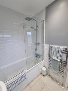 a white bathroom with a shower and a toilet at The Retreat, Cromer in Cromer