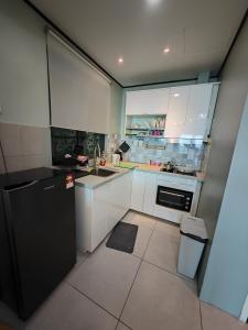 La cuisine est équipée de placards blancs et d'un réfrigérateur noir. dans l'établissement Modern Comfy Suite Room-9Pax, à Perai