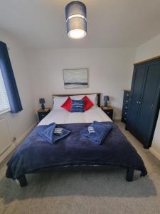 The Retreat, Cromer في كرومر: غرفة نوم بسرير كبير مع شراشف زرقاء ومخدات حمراء