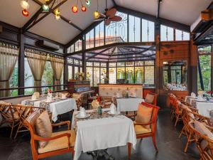 um restaurante com mesas e cadeiras brancas e janelas em Ancient Huế Garden Houses em Thôn Dương Xuân Hạ