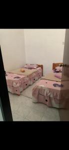 two beds in a room with pink sheets at R&R HOMESTAY TAMAN HARMONI in Simpang Renggam