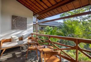 einen Balkon mit einem Sofa, einem Tisch und Stühlen in der Unterkunft Dinara Ubud in Ubud