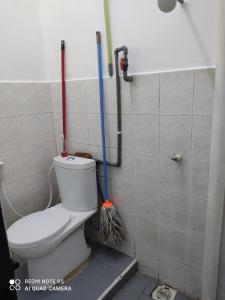 a bathroom with a toilet and two mop at R&R HOMESTAY TAMAN HARMONI in Simpang Renggam