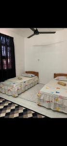 two beds in a room with a checkered floor at R&R HOMESTAY TAMAN HARMONI in Simpang Renggam