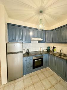 a kitchen with blue cabinets and a stainless steel refrigerator at Sunset View Balcon del Atlantico fase IV in Torviscas in Adeje