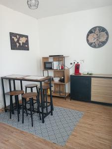 ein Wohnzimmer mit einem Tisch, Stühlen und einer Uhr in der Unterkunft Maison EL Marielle in Vierzon