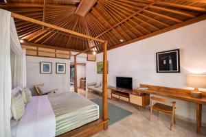 a bedroom with a bed and a desk and a television at Dinara Ubud in Ubud