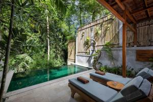 einen Pool in der Mitte einer Terrasse mit Stühlen und einem Tisch in der Unterkunft Dinara Ubud in Ubud