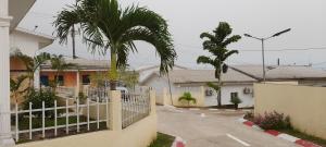 a fence in front of a house with a palm tree at CHEZ LIBAMA in Franceville