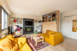 un soggiorno con divano giallo e tavolo di Bellevue - Superbe appartement avec vue, à pont de Sèvre a Boulogne-Billancourt