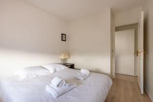 una camera da letto con un letto bianco e asciugamani di Bellevue - Superbe appartement avec vue, à pont de Sèvre a Boulogne-Billancourt