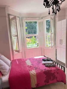 um quarto com uma cama rosa e 2 janelas em Bournemouth. Private Self Contained space. em Bournemouth
