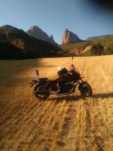 een motorfiets geparkeerd in een veld met bergen op de achtergrond bij Hotel Jaqués in Jaca