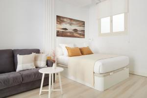 a white bedroom with a bed and a couch at Pension El Puerto in San Sebastián