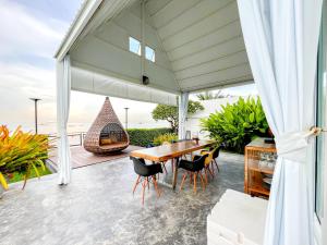 an outdoor patio with a wooden table and chairs at One Villa Samaesarn in Ban Samae San