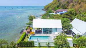 an aerial view of a house with a swimming pool and the ocean at One Villa Samaesarn in Ban Samae San