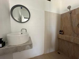 Baño blanco con lavabo y espejo en Cozy house in Chaloklum, en Mae Haad