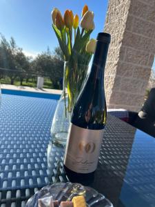 a bottle of wine and a vase of flowers on a table at Vila Milanezi in Višnjan