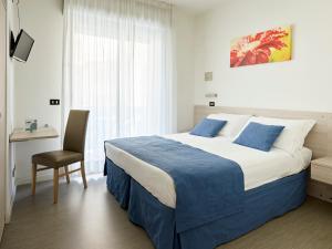a bedroom with a bed and a chair and a window at Hotel Bahia in Lignano Sabbiadoro